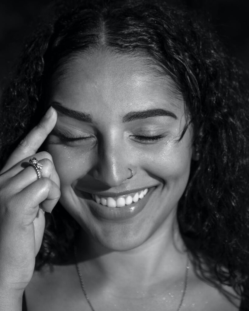 monochrome photo of smiling woman touching her eyebrow