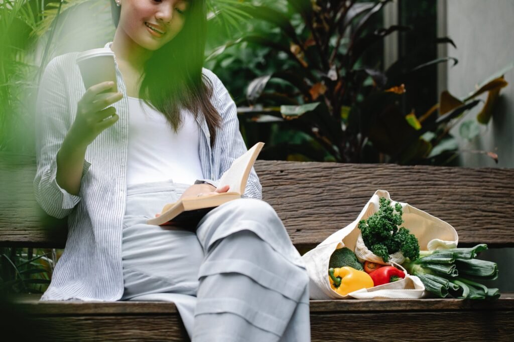 crop happy asian woman reading book on bench in garden